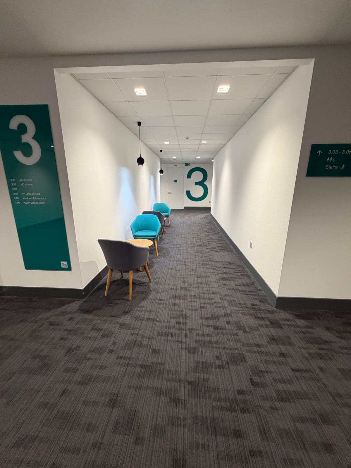 A third floor corridor with large teal floor numbering and a directory panel listing the suites on that floor