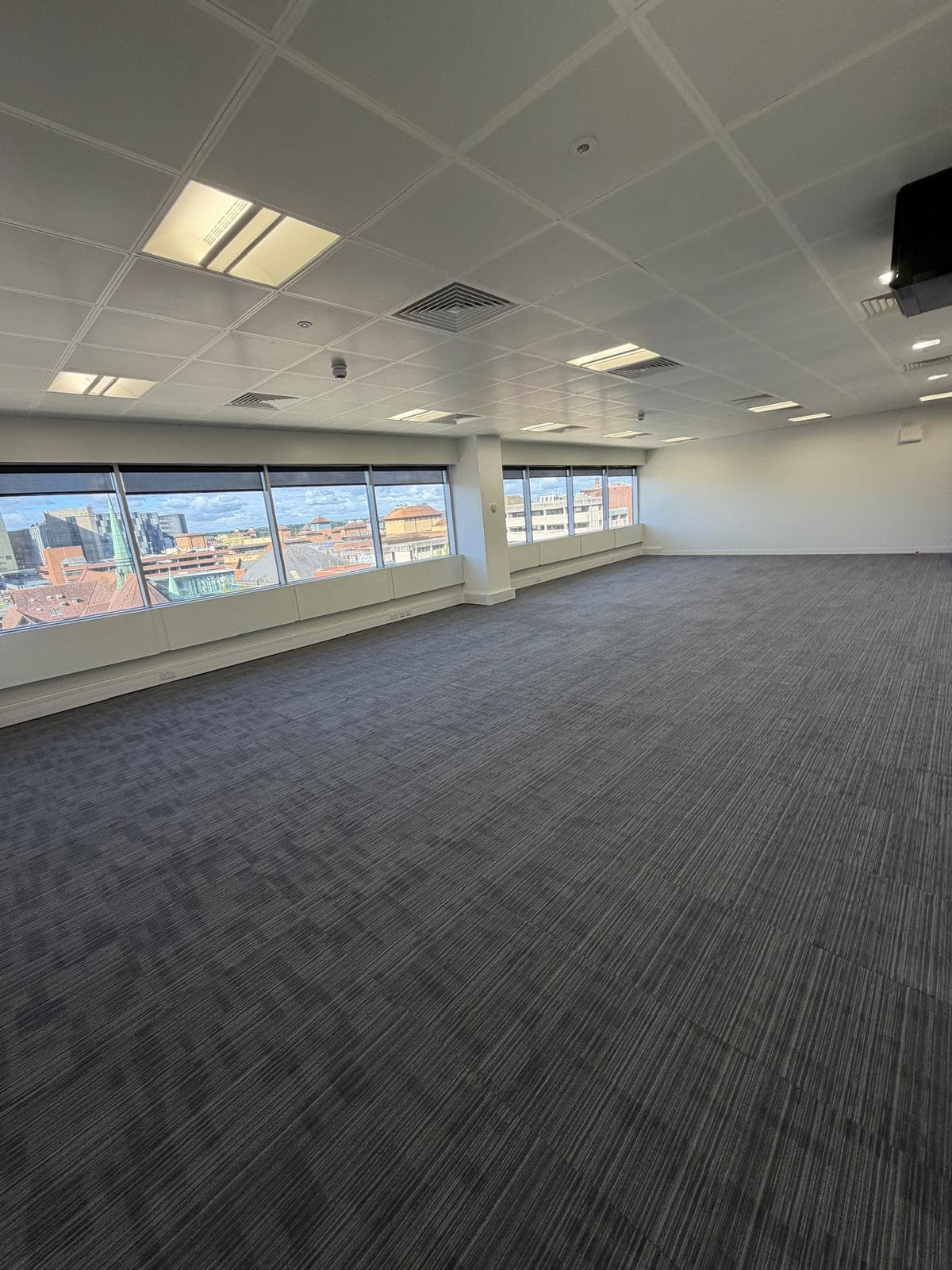 An empty suite ready to fit out, with a wall-mounted screen and a run of windows above the town