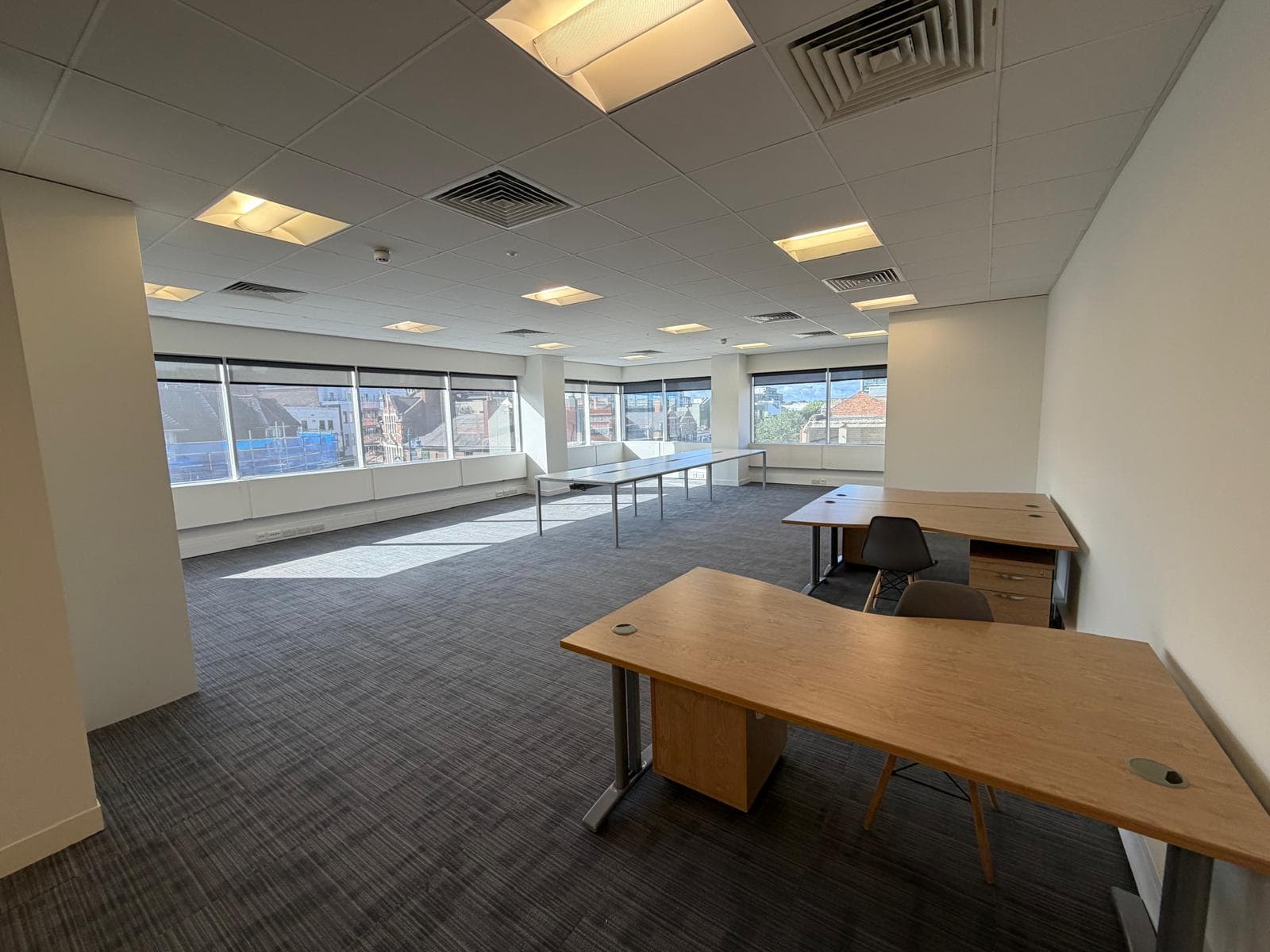 An office suite with oak desks in place and windows running the length of one wall
